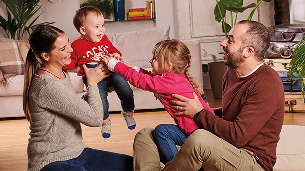 Parents and two young children sharing a playful moment at home